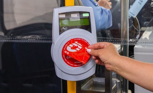 Customer waving their METRO Q® Fare Card at the fare validator upon boarding a METRO curb2curb shuttle.